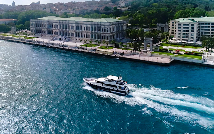 Bosphorus yacht cruising past Dolmabahçe Palace, Istanbul, aerial view.