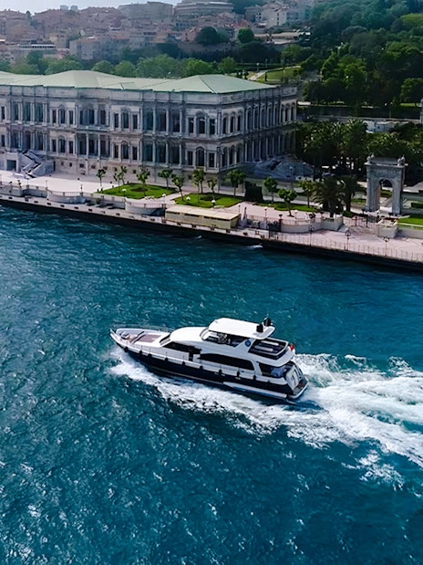 Bosphorus yacht cruising past Dolmabahçe Palace, Istanbul, aerial view.
