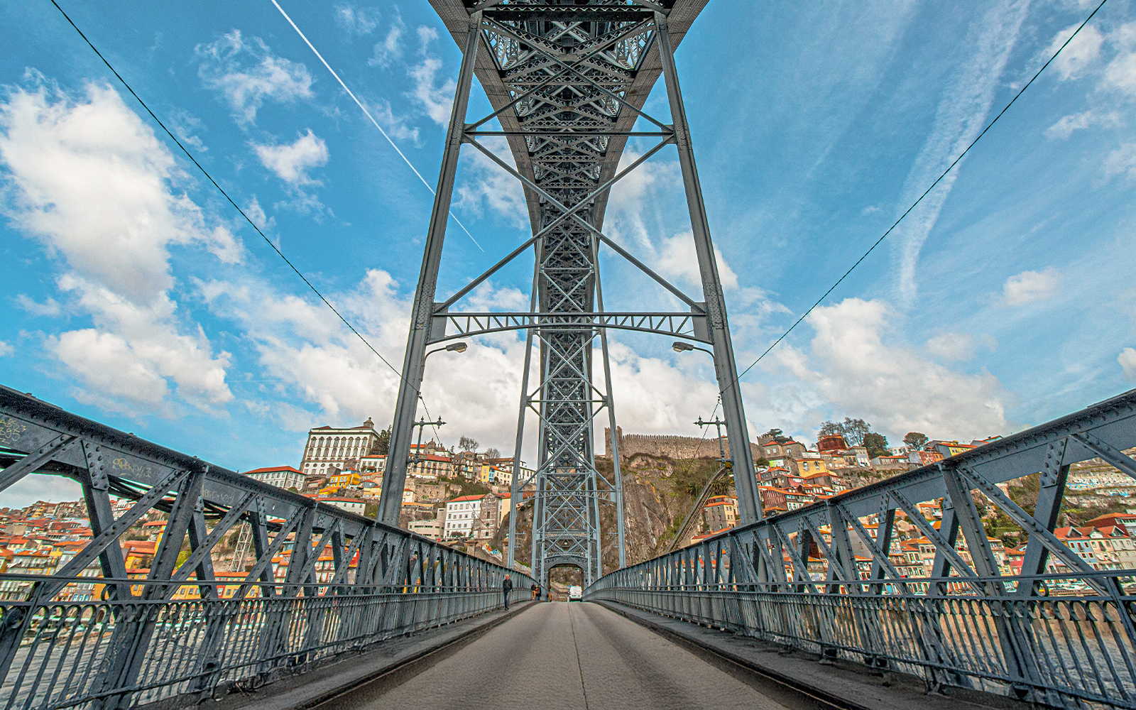 Tourist walking on Ponte D. Luís bridge in Porto with cityscape view.