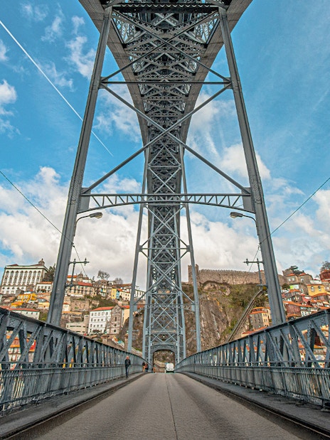 Tourist walking on Ponte D. Luís bridge in Porto with cityscape view.