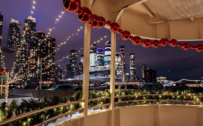 Harbor Lights Cruise with city skyline and festive decorations at night.