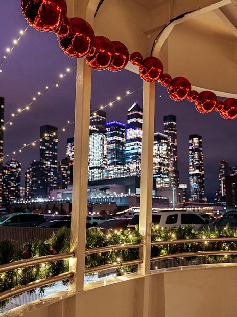 Harbor Lights Cruise with city skyline and festive decorations at night.