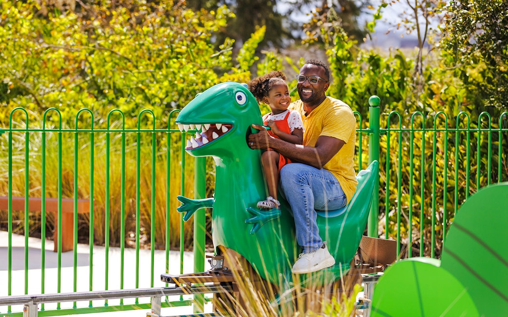 Father and child on dinosaur ride at Peppa Pig Theme Park, Florida.
