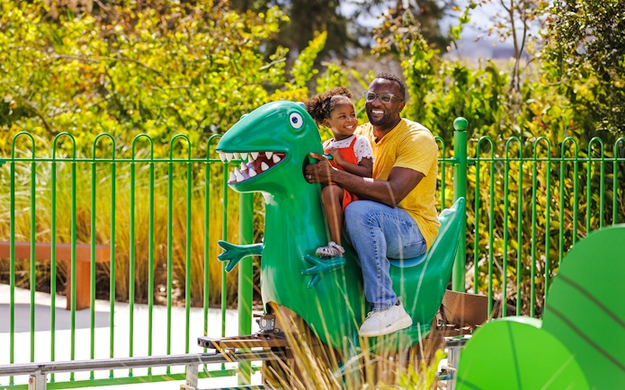 Father and child on dinosaur ride at Peppa Pig Theme Park, Florida.