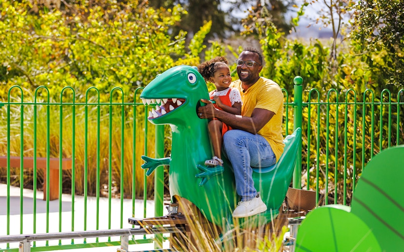 Father and child on dinosaur ride at Peppa Pig Theme Park, Florida.