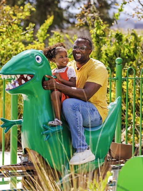 Father and child on dinosaur ride at Peppa Pig Theme Park, Florida.