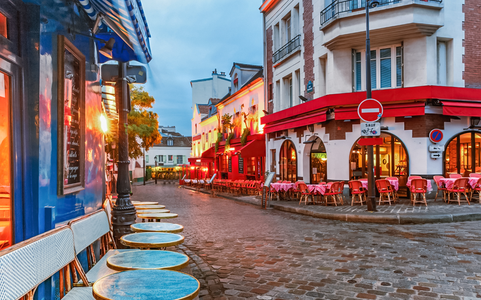 Montmartre street with cafes and red awnings in Paris, ideal for audio guide exploration.