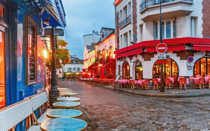 Montmartre street with cafes and red awnings in Paris, ideal for audio guide exploration.