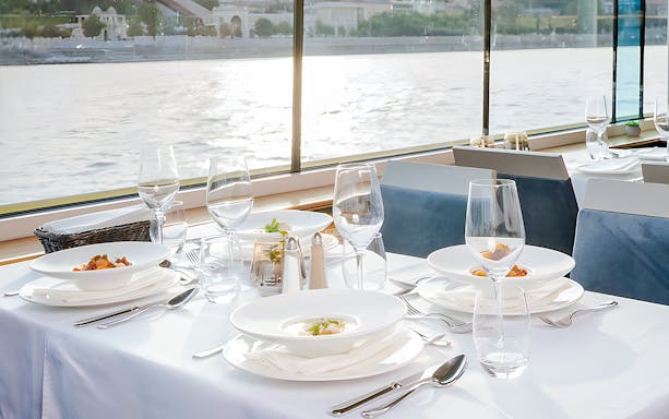 Dinner table set on Danube cruise in Budapest with river view.