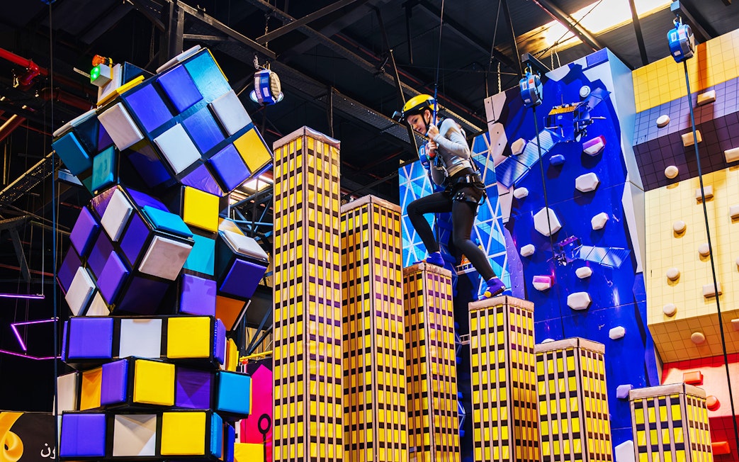 Climber navigating colorful obstacle course at Loco Bear Entertainment Hub.