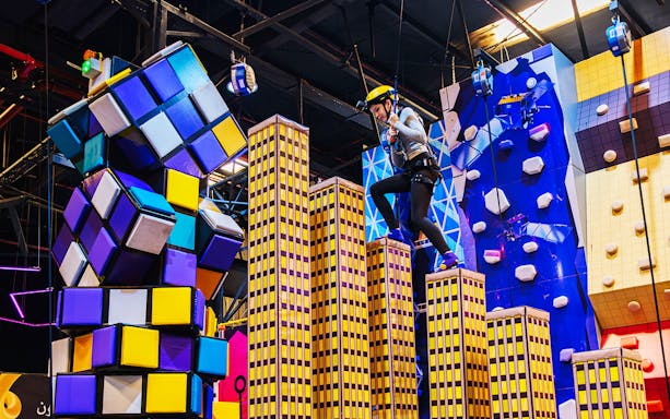 Climber navigating colorful obstacle course at Loco Bear Entertainment Hub.