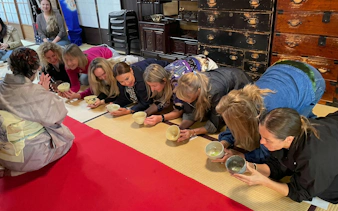 Tourists participating in a traditional tea ceremony in a Kyoto tea room.