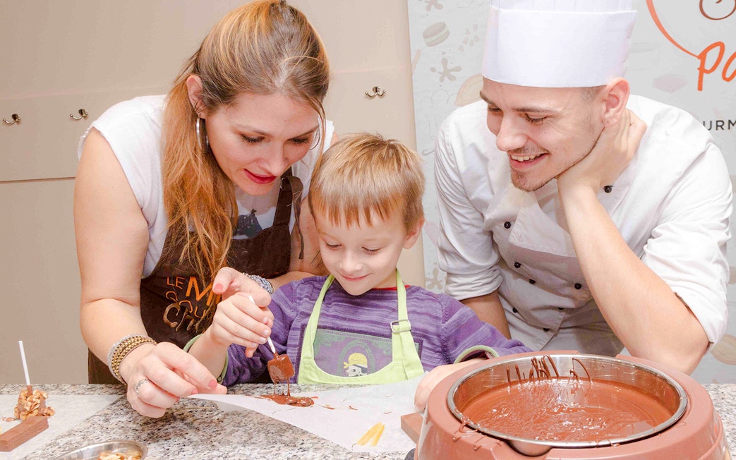 Chocolate chef guiding child in chocolate-making at Choco-Story Paris.