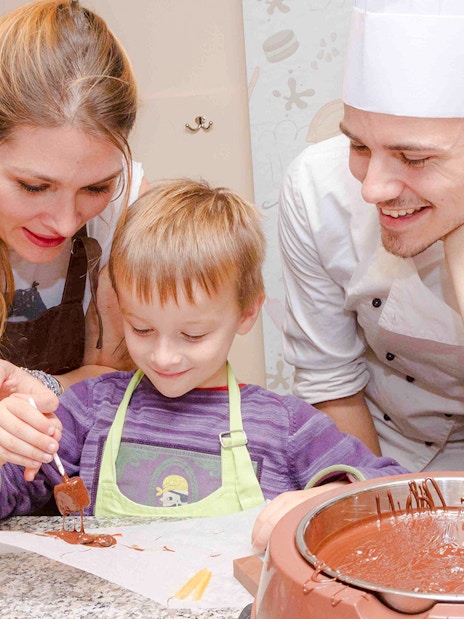 Chocolate chef guiding child in chocolate-making at Choco-Story Paris.