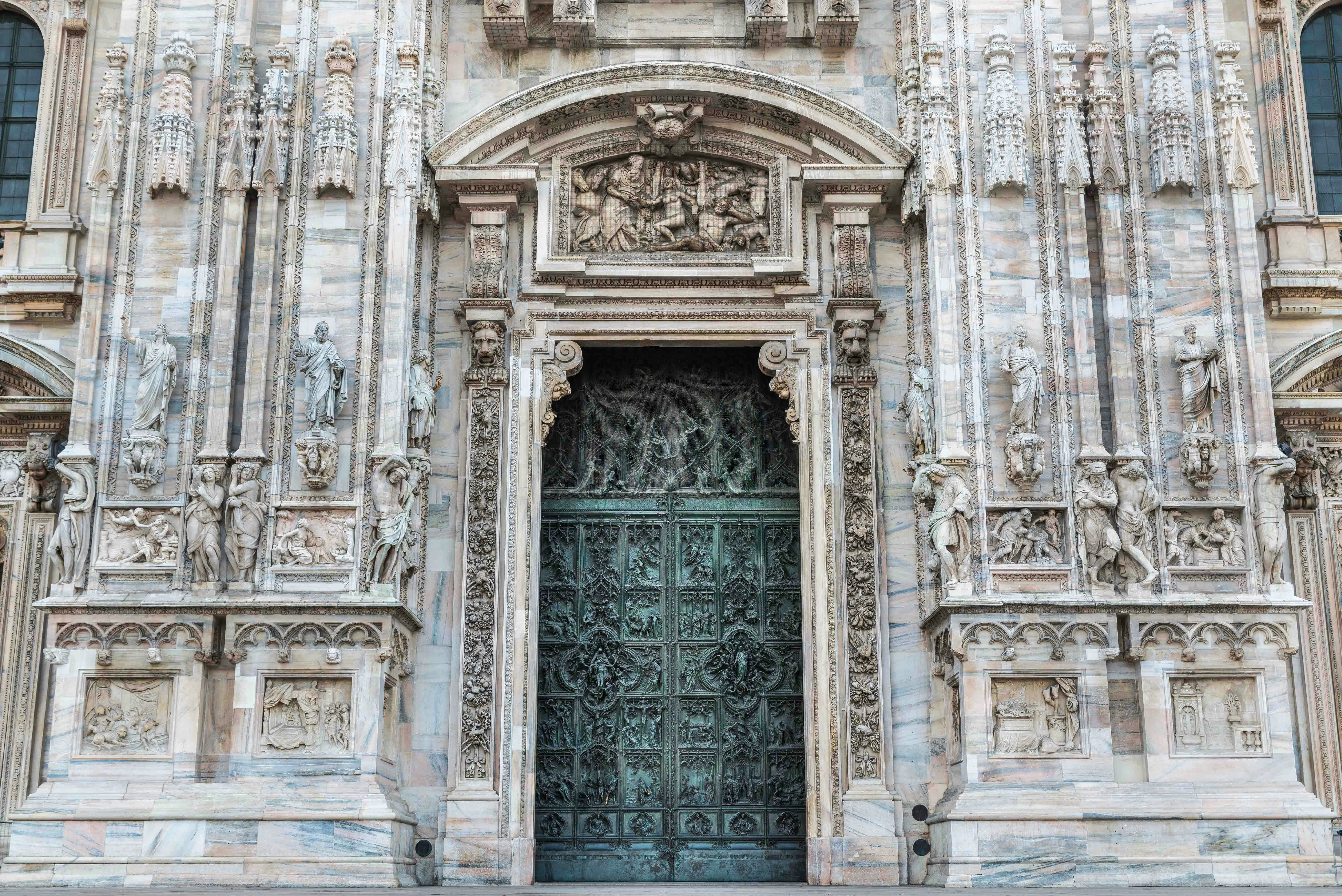 Milan Duomo's ornate doors with intricate religious carvings.