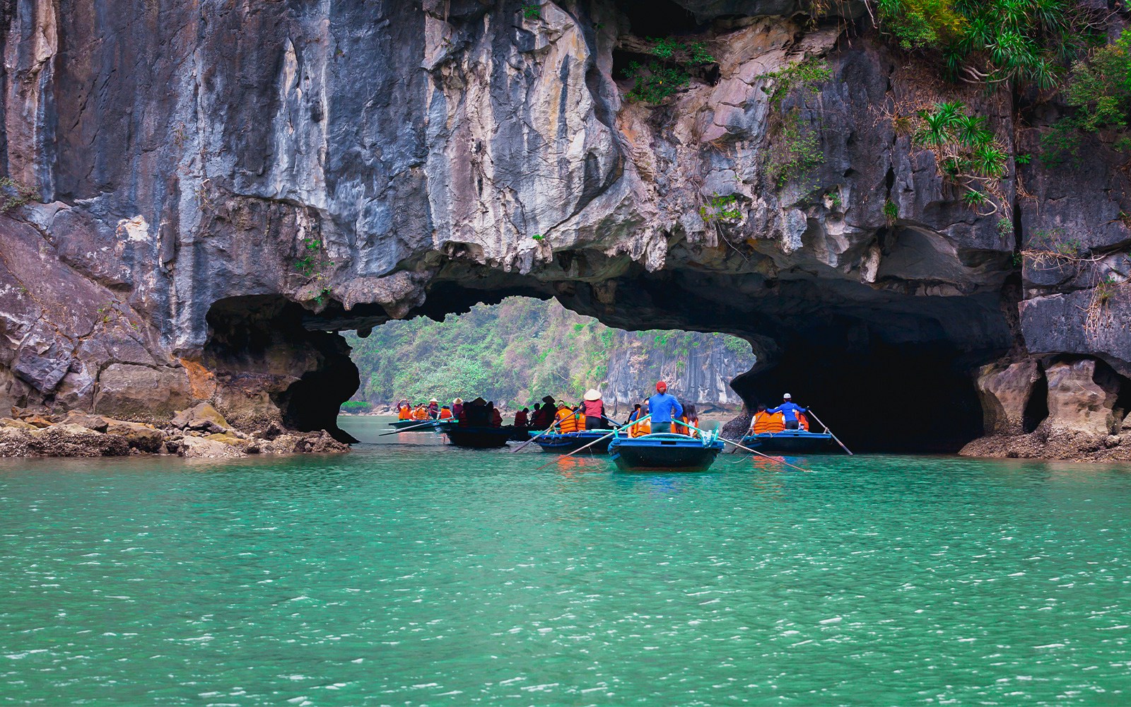 Boats entering a limestone cave on a 1-Day Deluxe Cruise in Halong Bay.