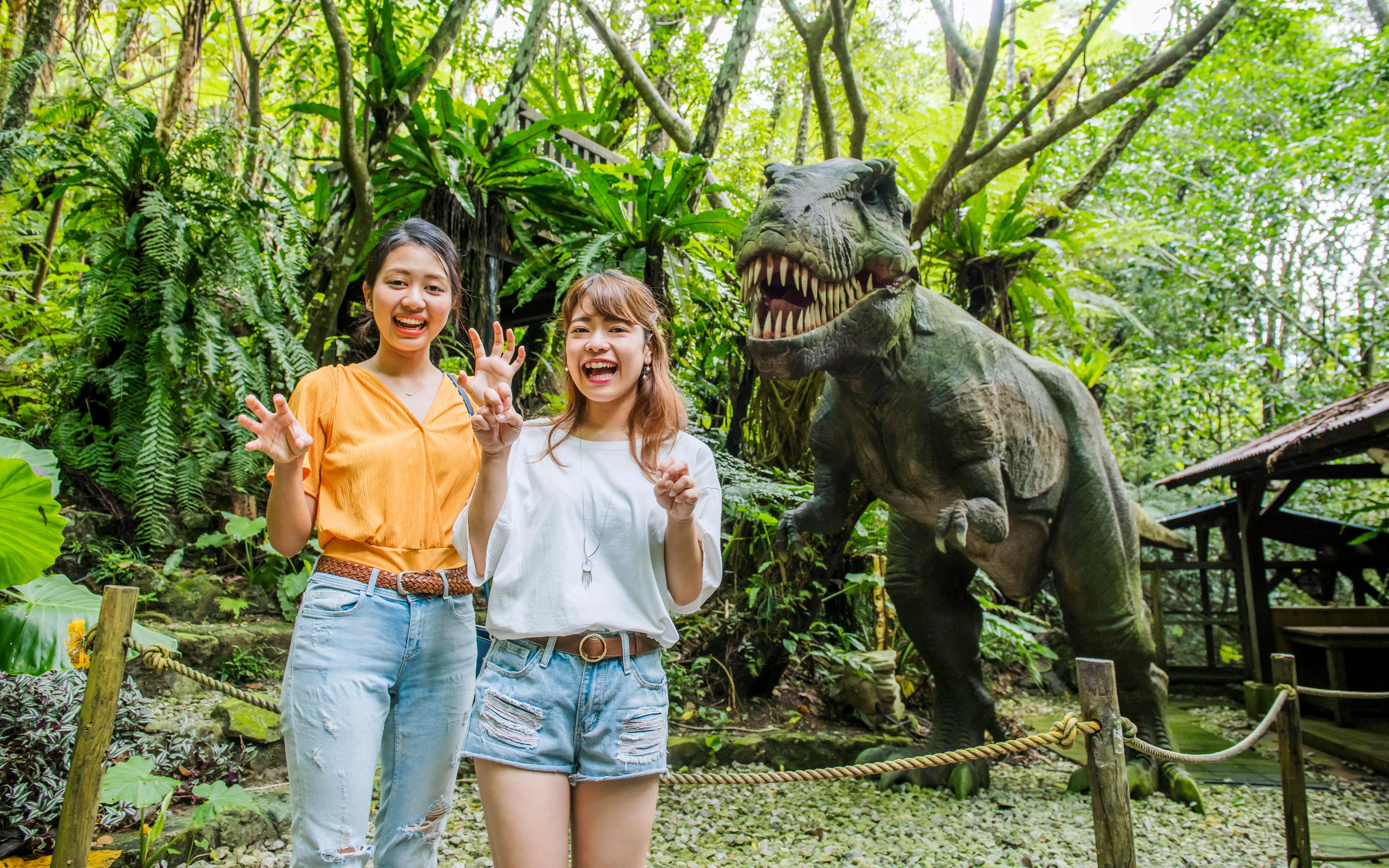 Visitors posing with dinosaur statue at Okashigoten Nago Dino Park Yanbaru Subtropical Forest.