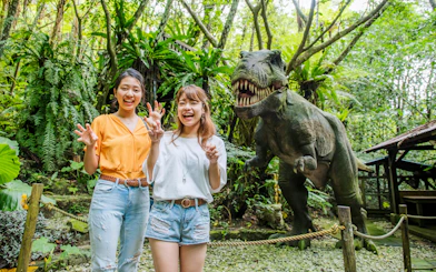 Visitors posing with dinosaur statue at Okashigoten Nago Dino Park Yanbaru Subtropical Forest.