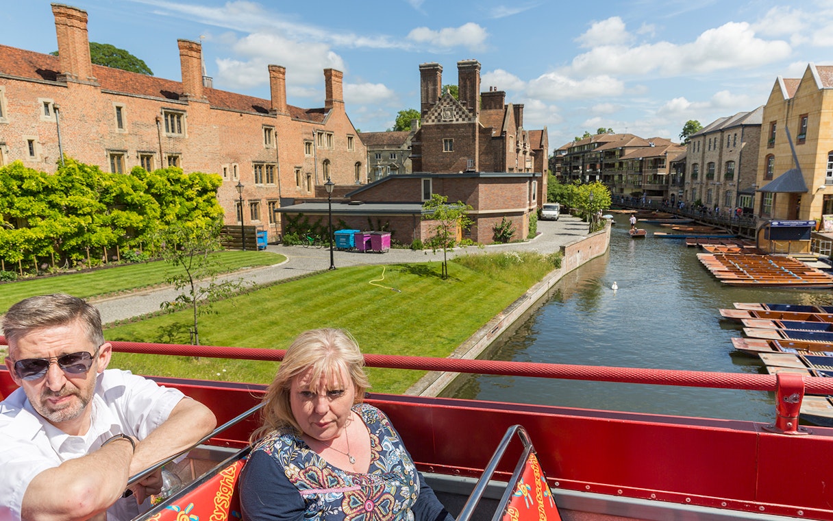 Cambridge Hop-On Hop-Off bus near historic buildings and River Cam.