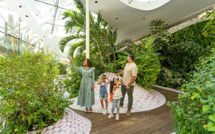 Family exploring lush greenery inside Al Noor Island Butterfly House, Sharjah.