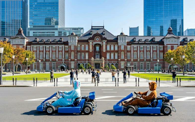 Tourists go-karting in costumes in front of Tokyo Station.