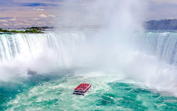 Boat tour approaching Niagara Falls, Canada with mist rising from the waterfall.