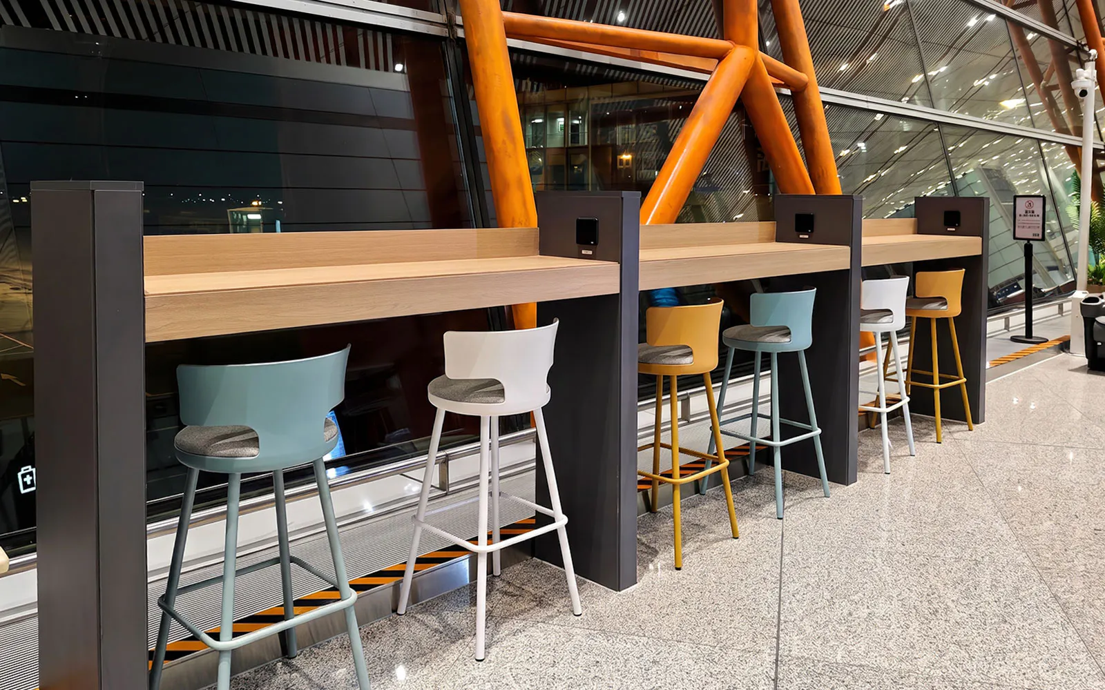 Seating area with colorful chairs and charging stations at Terminal 3 Beijing Capital Airport.