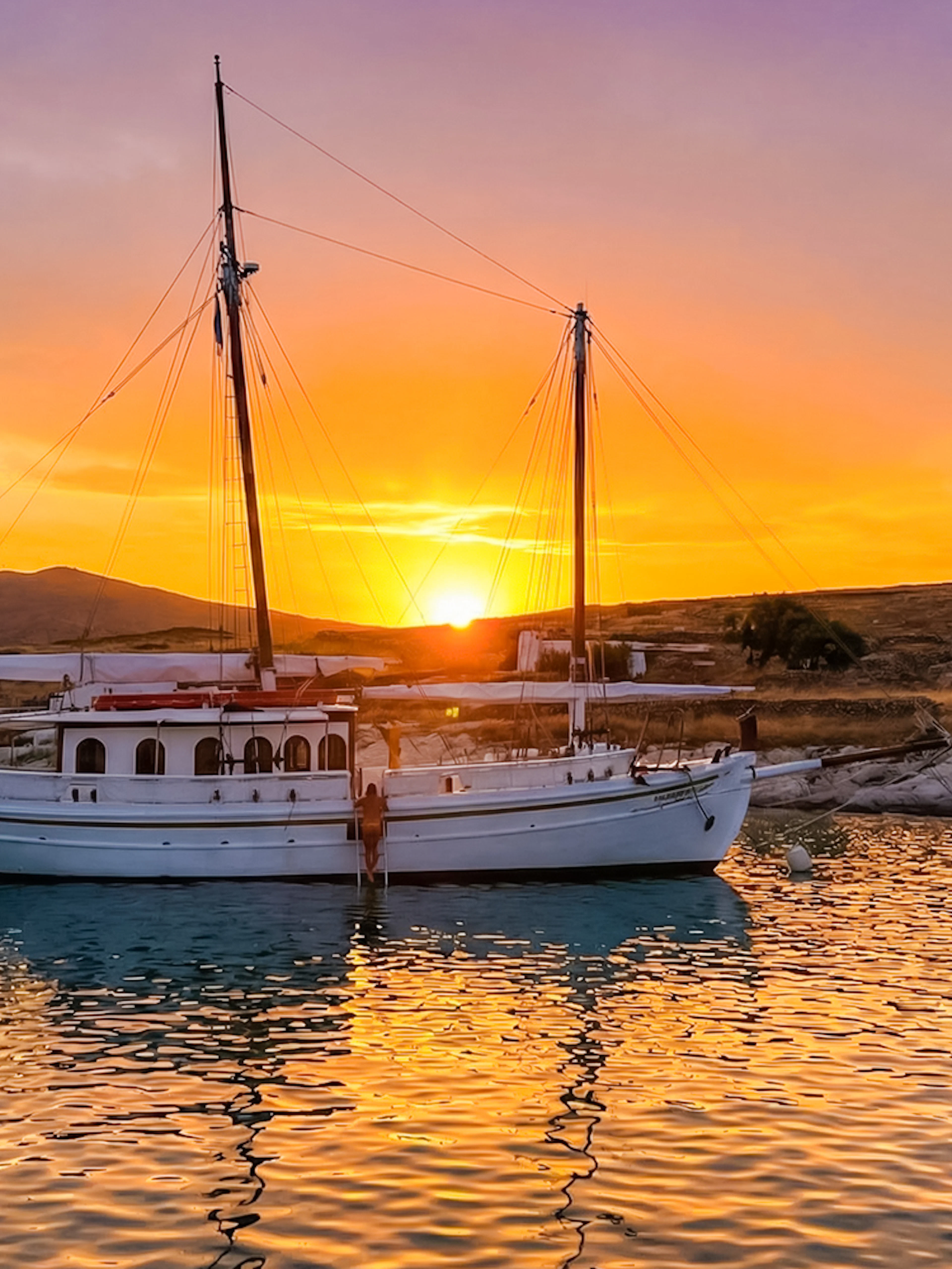Classic boat anchored at sunset near Corfu coast.