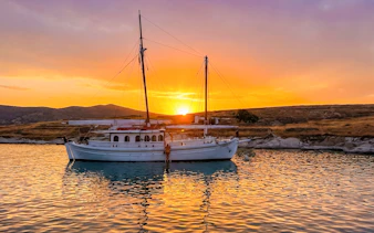 Classic boat anchored at sunset near Corfu coast.