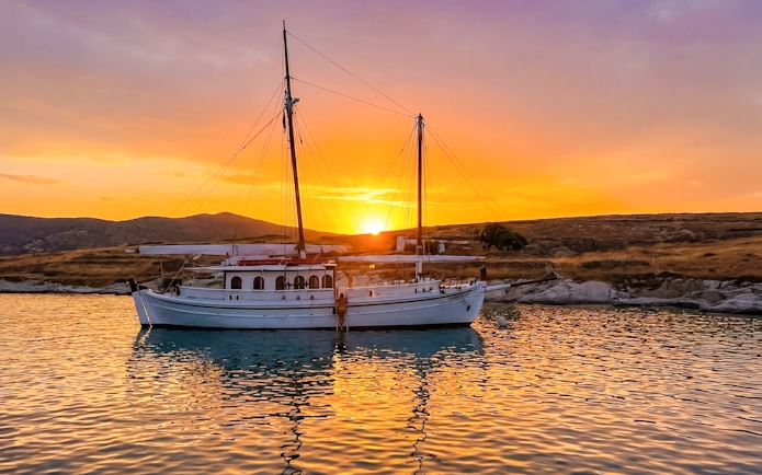Classic boat anchored at sunset near Corfu coast.