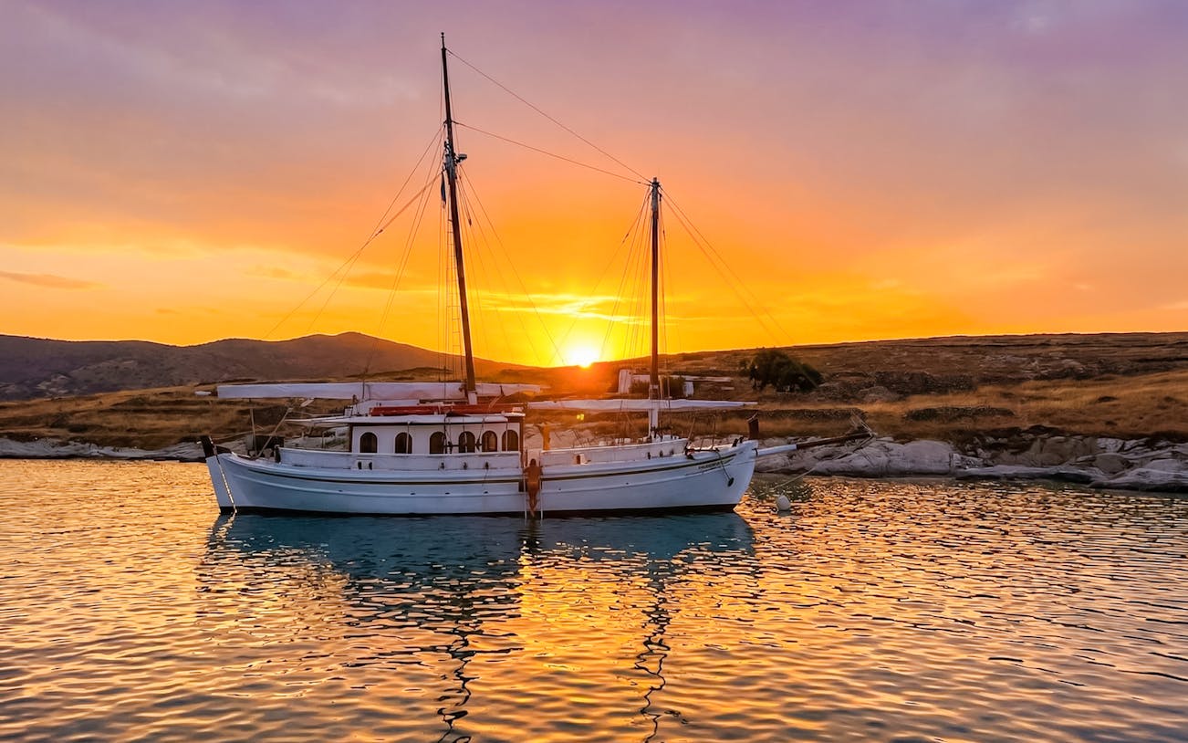Classic boat anchored at sunset near Corfu coast.