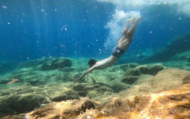 Young man snorkeling over rocky seabed in Costa Brava.