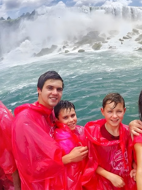 Tourists in red ponchos on a Niagara Falls cruise with waterfalls in the background.