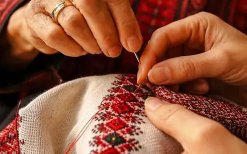 Hands sewing traditional Moroccan embroidery at a workshop in Marrakesh.