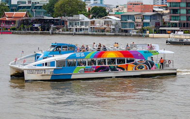Chao Phraya tourist boat on Bangkok river with colorful design and passengers on deck.