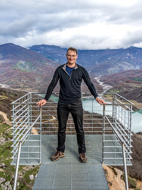Tourist on viewing platform overlooking Gamti mountains and river.