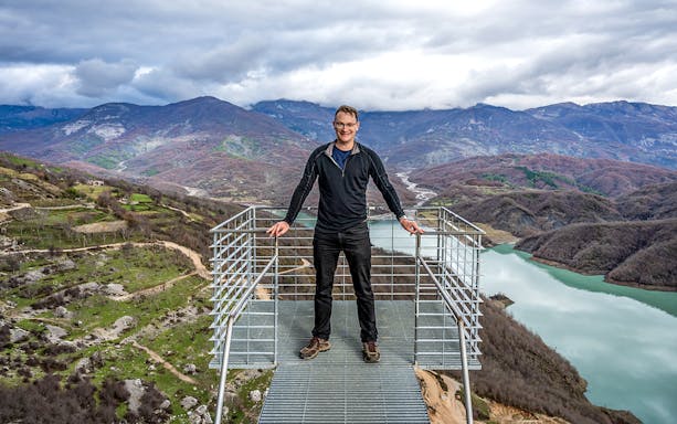 Tourist on viewing platform overlooking Gamti mountains and river.