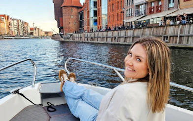 Guest relaxing on a boat during Gdańsk Motława Sunset Cruise with cityscape view.
