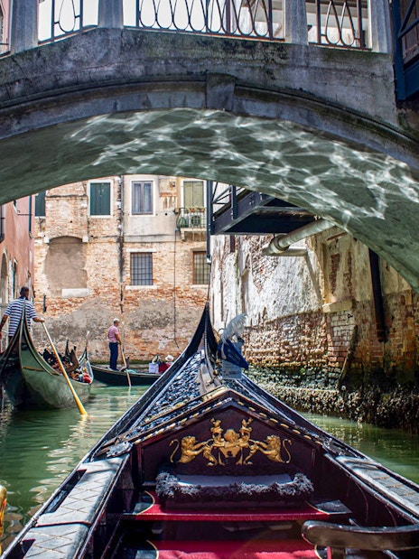Gondola ride under a bridge in Venice, Italy, part of the Venice City Pass attractions.
