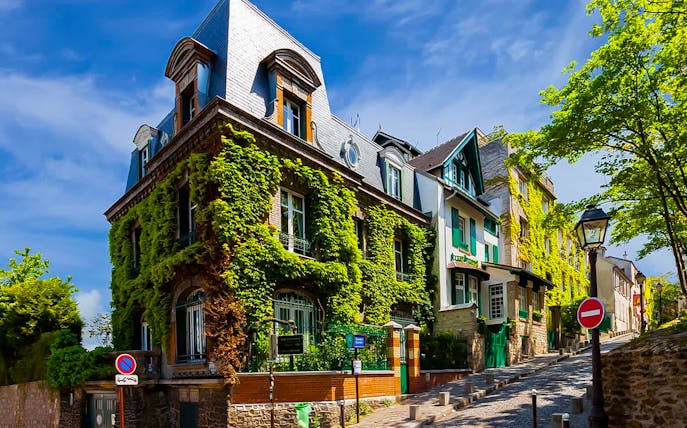 Montmartre street with ivy-covered buildings, part of a romantic walking tour in Paris.