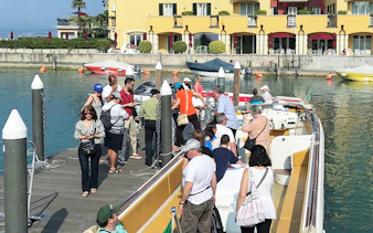 Tourists boarding a boat for a guided full-day tour of Lake Garda.