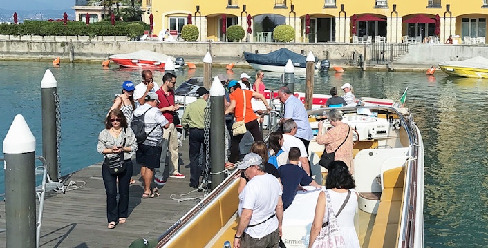 Tourists boarding a boat for a guided full-day tour of Lake Garda.