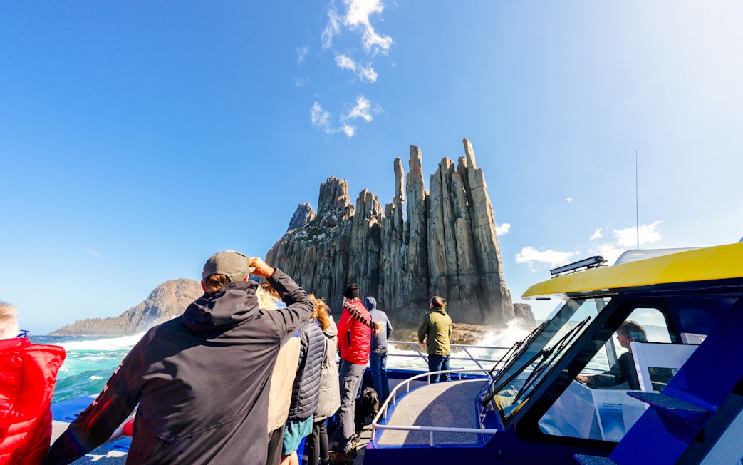 People on a boat viewing Cape Raoul cliffs during a cruise.