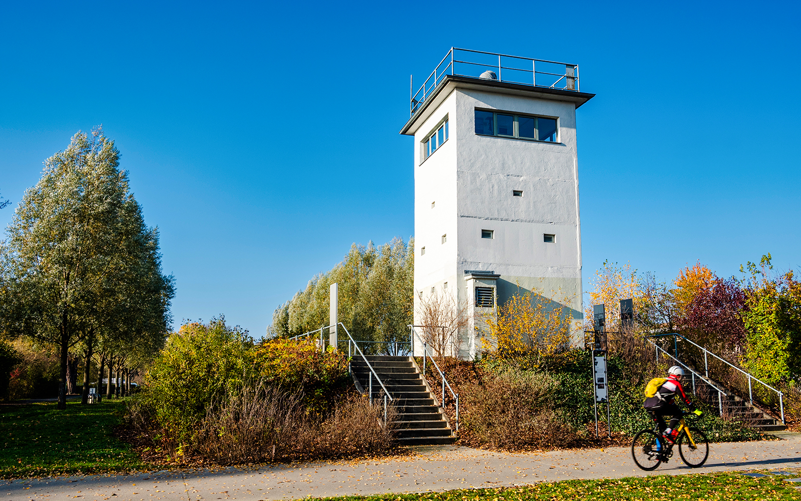 Nieder Neuendorf watchtower in Berlin with cyclist on path.