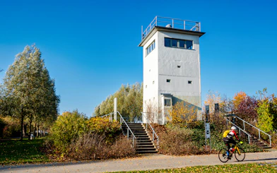 Nieder Neuendorf watchtower in Berlin with cyclist on path.