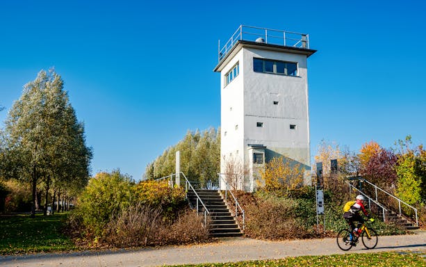 Nieder Neuendorf watchtower in Berlin with cyclist on path.