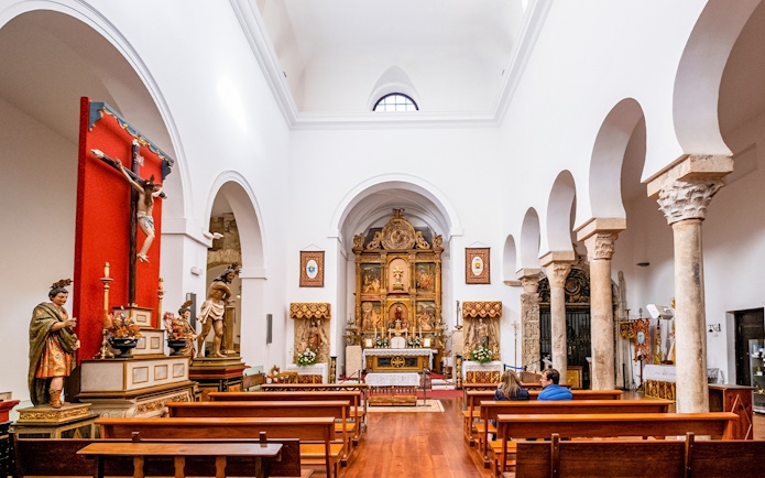 Interior of El Salvador Church in Toledo with altar and religious statues.