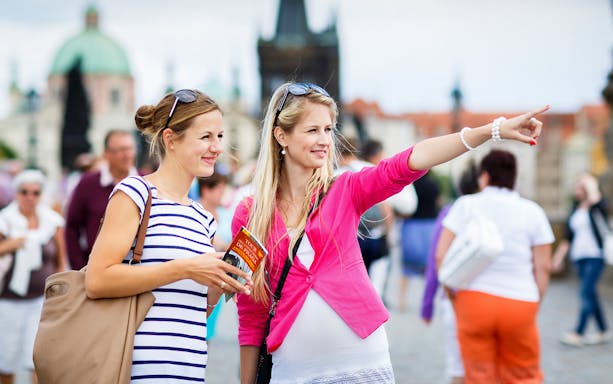 Tourists exploring Prague Castle with guidebook in hand.