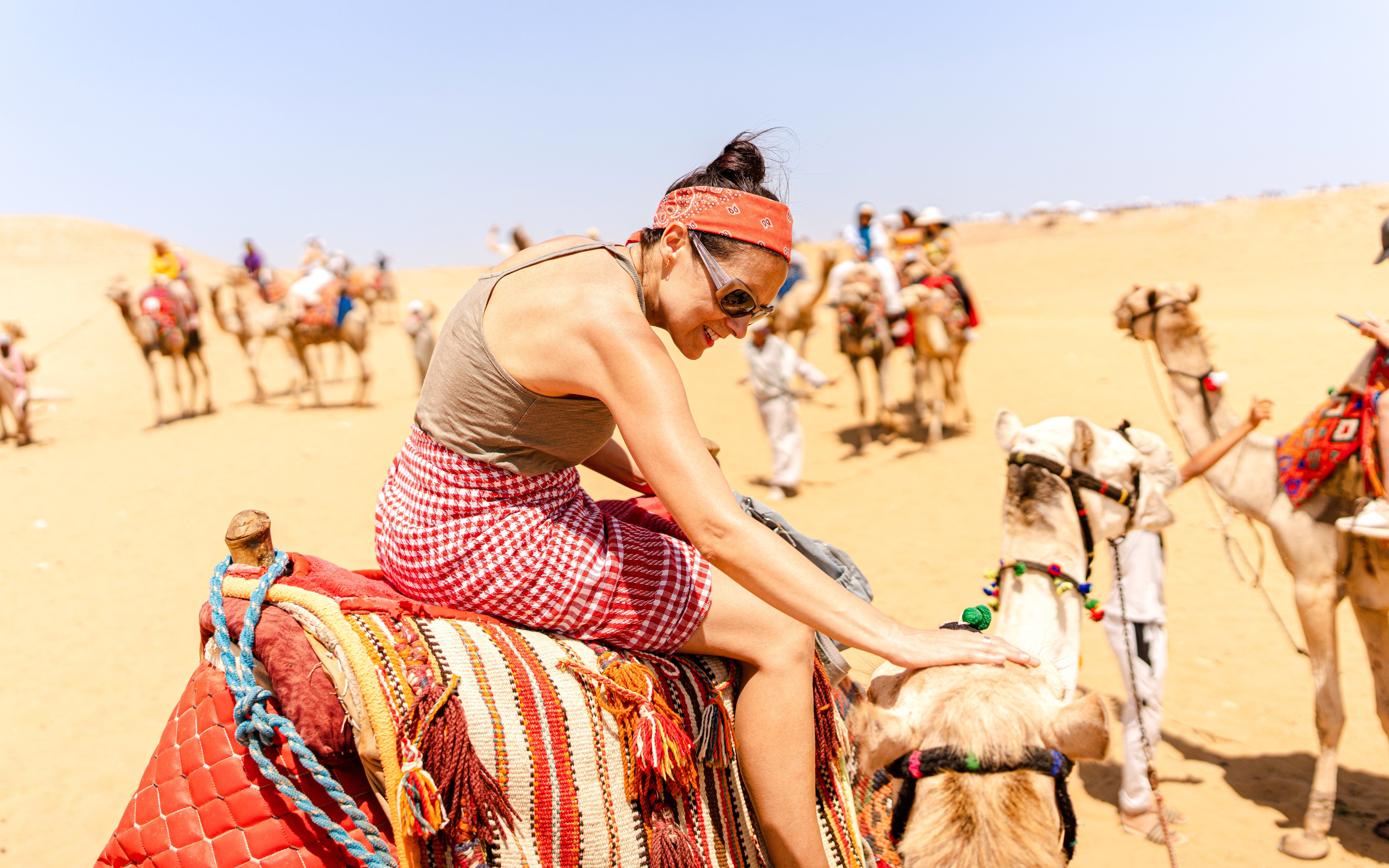 Camel ride experience at Giza Complex with tourists in the background.