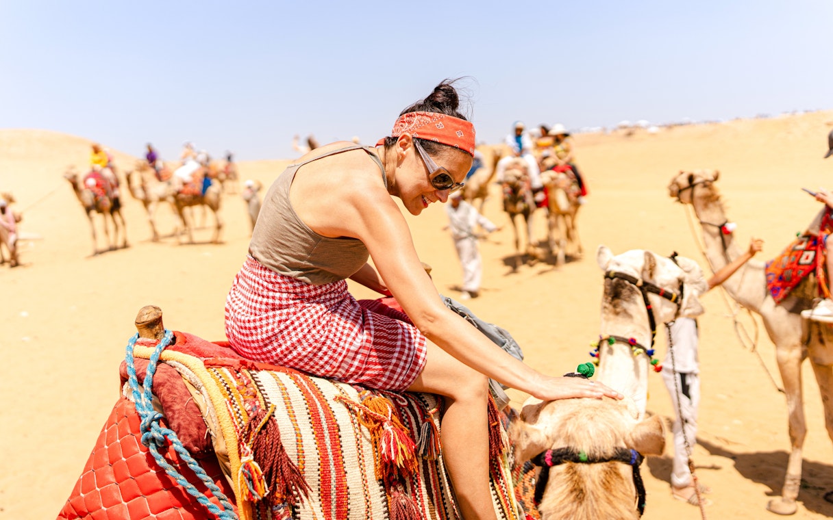 Camel ride experience at Giza Complex with tourists in the background.